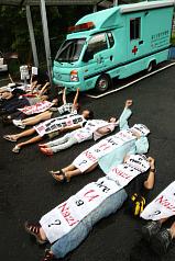 動物保護團體27日在台北市內湖動物之家，躺在動物救援車前，抗議台北市政府捕捉流浪狗的政策，呼籲市府懲罰棄養的飼主等源頭管制。圖片來源：中央社   