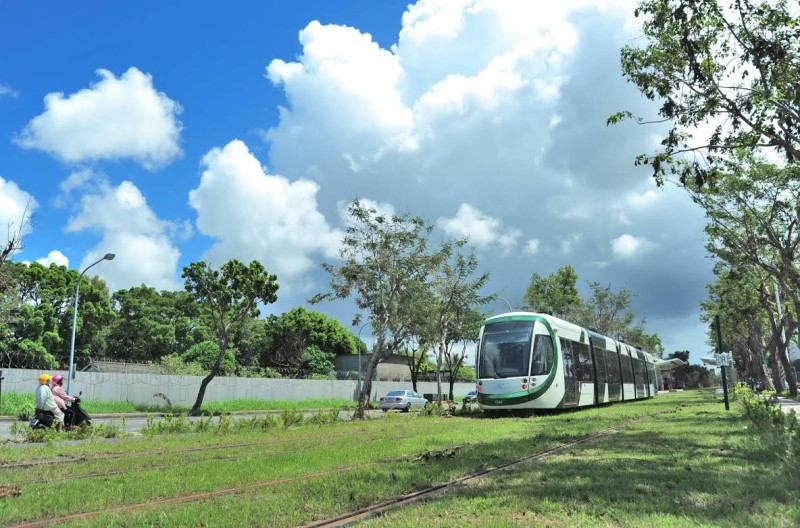 輕軌上路象徵高雄在綠能公共運具、節能減碳大躍進，輕軌列車穿捘綠意盎然的市區道路，頻添高雄都市風情。圖：高雄市政府提供   
