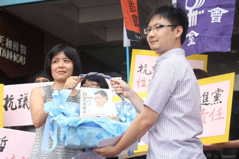 民進黨社會運動部副主任陳子瑜（右）從台灣守護民主平台理事陳昭如（左）手上接下籃子，裡頭放著被批評有歧視女性言論的柯文哲著作《白色的力量》和石頭。圖2之2：林雨佑/攝   