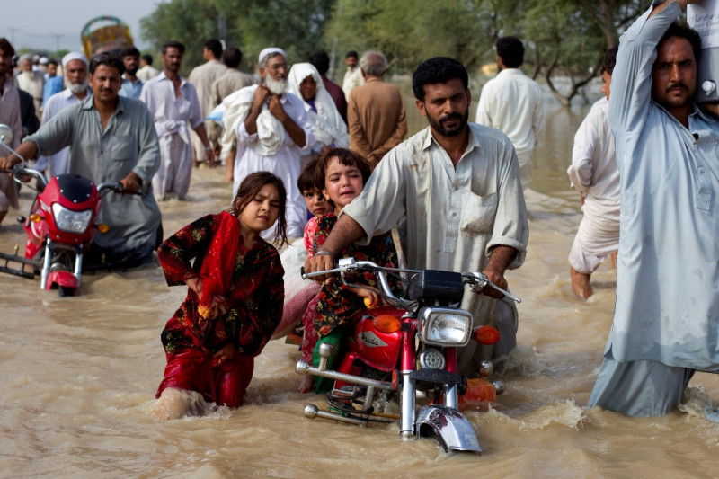 巴基斯坦連日大雨造成洪水蔓延，民眾不得不帶著孩子涉水而過尋找安全避難所。圖片來源：達志影像/路透社   