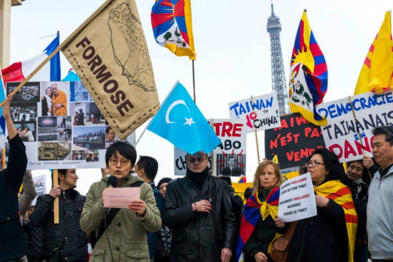 巴黎鐵塔廣場台灣留學生演講，右二為越南團體代表,右一為中國民權人士。台灣學生自行設計了一只福爾摩莎旗來代表台灣。圖片來源：TEWA提供，Yen-chun Chen/攝影。   
