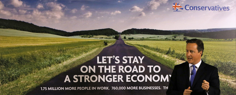 保守黨的英國首相卡麥隆，1月2日站在新的競選海報前，海報上的標語寫著：「讓我們留在通往更強壯經濟的路上」。圖片來源：達志影像/路透社。   