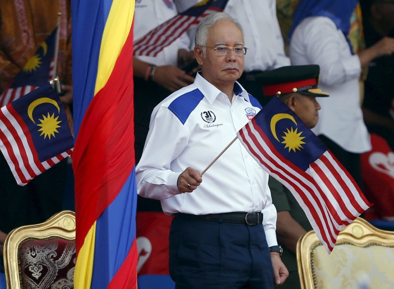 馬來西亞政府8月31日迎接2015國慶，受貪腐疑雲籠罩的首相納吉布揮舞國旗時，臉色凝重。圖片來源：達志影像/路透社   