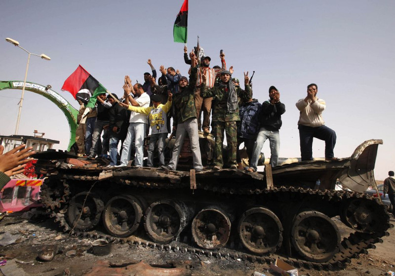 利比亞反政府民眾站在坦克車上，慶祝歐美聯軍對利比亞領導人格達費的軍隊展開空襲行動。圖片來源：達志影像/路透社。   