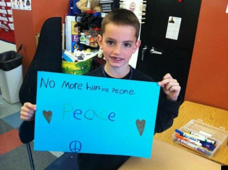 馬汀舉著自己做的標語「不要再傷害人♥和平♥」。照片來源：露西亞‧伯利(Lucia Brawley)。   