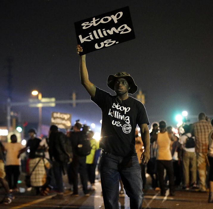 美國密蘇里州18歲黑人青年布朗遭警方槍殺事件，引發當地居民大規模抗議。其中，有非裔居民高舉「停止殺害我們」(Stop Killing Us)的標語，表達不滿。圖片來源：達志影像/美聯社。   
