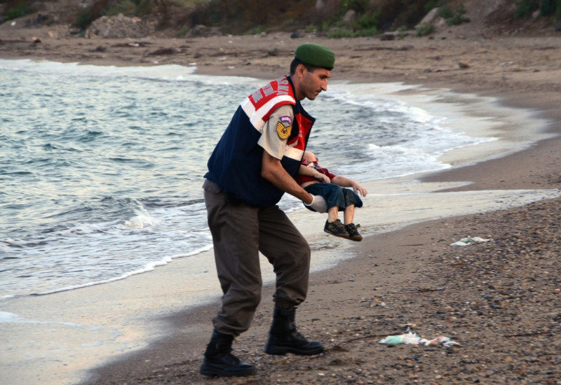 一位3歲的敘利亞男童阿蘭伏屍土耳其海岸，震驚全球，阿蘭的父親阿布杜拉說，「現在，我只想將2名兒子與妻子的遺體，帶回敘利亞科巴尼的老家埋葬。」圖為警察抱起溺斃的小孩。圖片來源：達志影像/美聯社資料照片   
