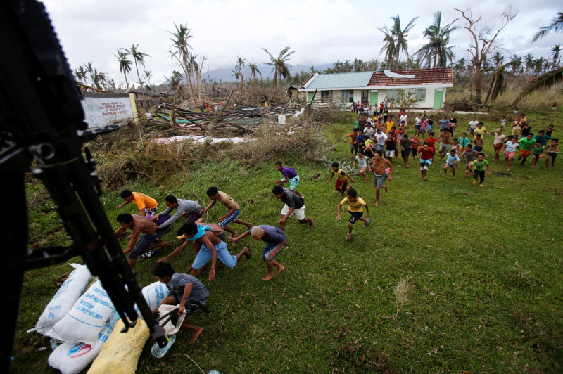 在受災最重的菲律賓雷伊泰島(Leyte)的中心都市獨魯萬市(Tacloban City)，超級強颱海燕的生還者正飛奔前往迎接由菲國空軍直升機派送的救災物資。美軍和菲國空軍空投白米、衣物、飲水到菲律賓中部人車難行的受災區。圖片來源：達志影像/路透社。   