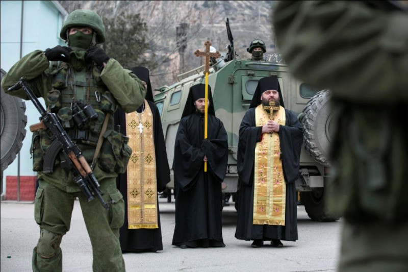 俄國軍隊進駐克里米亞的巴拉克拉瓦鎮，鄰接烏克蘭邊境哨所。東正教僧侶則在一旁祈禱和平。圖片來源:達志影像/路透社   