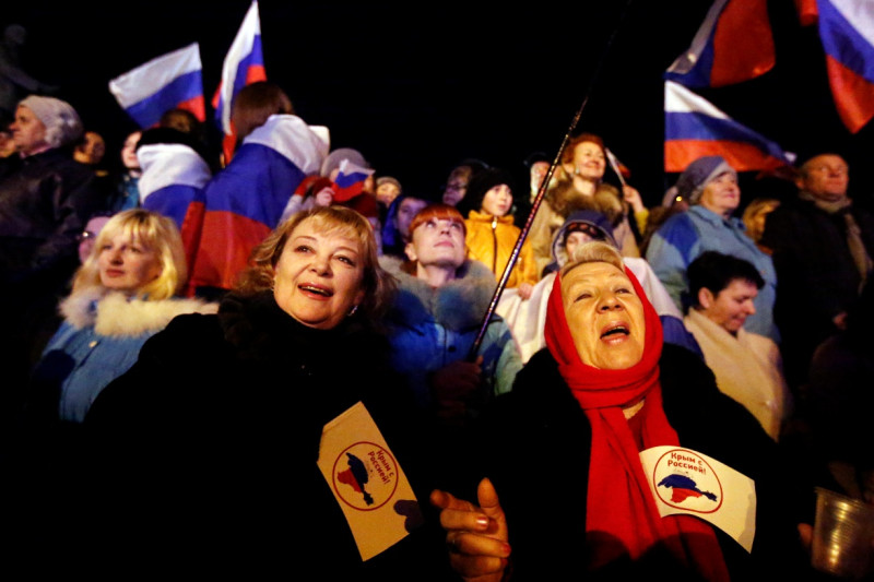 兩名克里米亞女性揮舞旗幟，上面寫著「克里米亞和俄羅斯同在」。她們正在克里米亞首都辛菲洛普(Simferopol)列寧廣場上等待公投的初步結果。圖片來源：達志影像/路透社。   