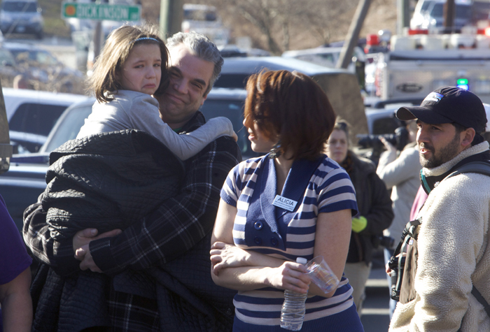 美國康乃狄克州西部新鎮（Newtown）昨（14）日發生校園槍擊案，倖存學童臉上驚魂未定，父母則安慰懷中的子女。圖片來源：達志影像/路透社   