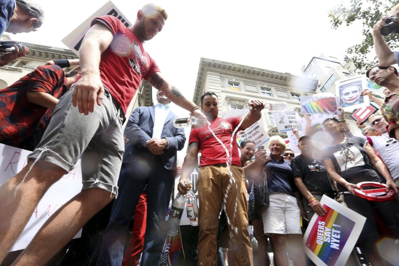紐約同性戀者將伏特加倒在人行道上，以抗議俄國通過歧視同性戀者的法案，示威者還將普亭照片畫成電影「黑暗騎士」裡的惡人小丑。圖片來源：達志影像/美聯社。   