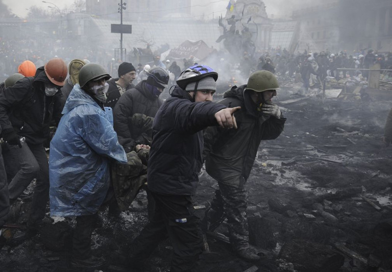 烏克蘭首都基輔20日再爆發新一波流血衝突。圖為在獨立廣場的示威者抬著傷者就醫。圖片來源：達志影像/路透社   