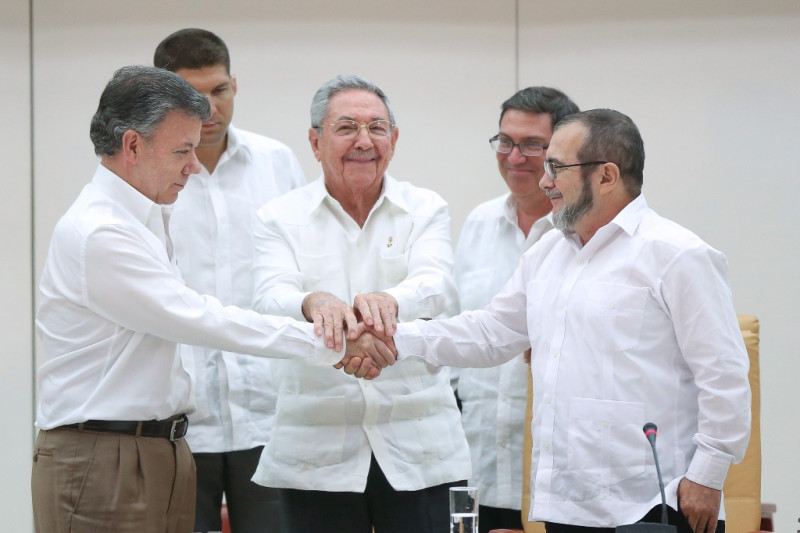 在古巴總統卡斯楚(中)的見證下，哥倫比亞總統桑托斯(左)與哥倫比亞革命軍(FARC)指揮官隆多諾(右)週三(23日)共同宣布，雙方將在6個月內簽署和平協議。圖片來源：達志影像/路透社   