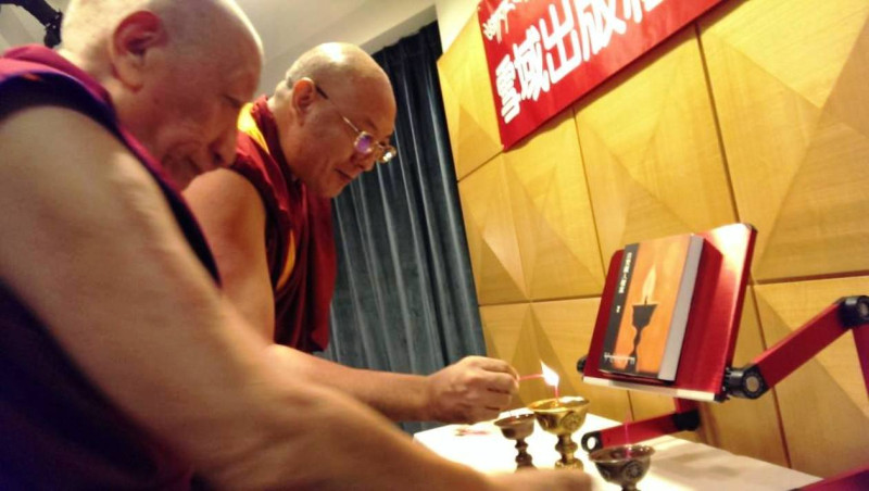 第一位由達賴喇嘛指派到台灣達賴喇嘛西藏宗教基金會的法師強巴加措格西(圖左)及現任基金會佛學教授師長見悲青增格西(圖中)，共同點燃酥油長明燈，為新書發表祈福。圖片2-1來源：鄭凱榕/攝。   