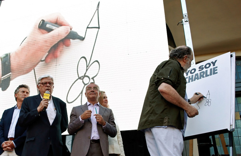 阿根廷首都布宜諾斯艾利斯的幽默博物館前，漫畫家山卓(圖右)在「我是查理」(西班牙文：Yo Soy Charlie)的畫布上畫上一支鉛筆，向《查理周刊》致敬。圖片來源：達志影像/路透社。   