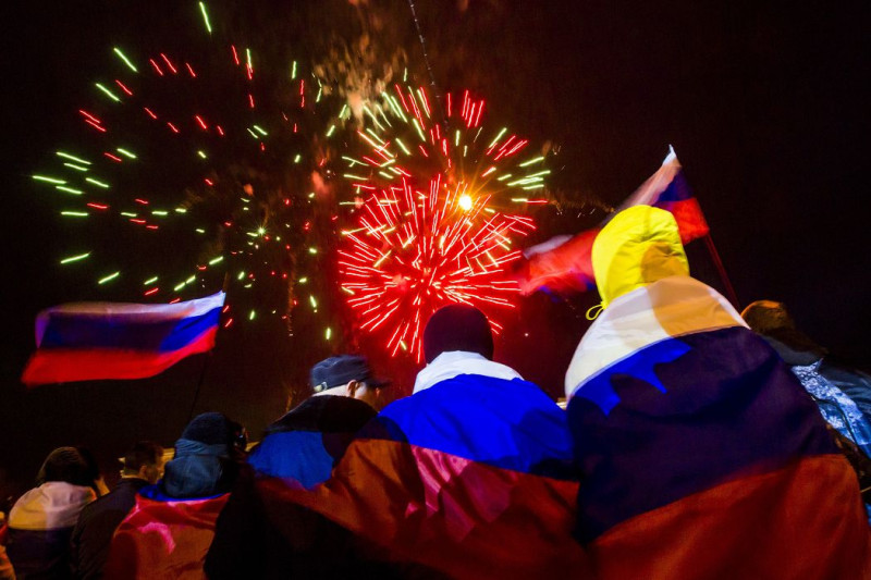 克里米亞16日在「脫烏入俄」公投初步結果出爐後，民眾披著俄羅斯國旗、觀看煙火慶祝。圖片來源：達志影像/路透社   