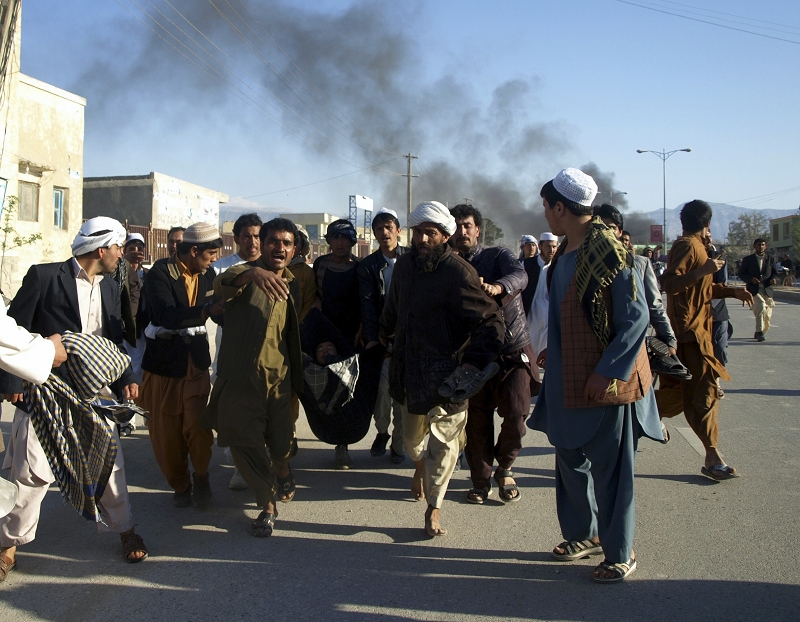 位於阿富汗北部城市馬薩里沙利夫市的聯合國辦公室遭群眾攻擊，不幸造成至少7名聯合國人員在內的14人喪生。圖為一名阿富汗民眾在1日的攻擊事件中受傷被旁人抬出，後方冒煙處就是聯合國辦公室。圖片來源：達志影像/路透社   