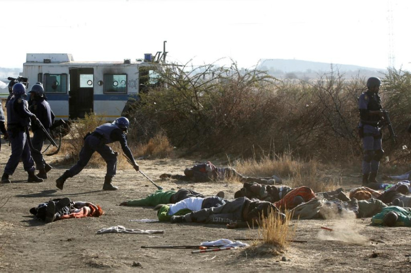 南非馬瑞康納礦場於16日發生大規模警民流血衝突，造成34人死亡，警察正檢查礦工屍體身上有否武器。圖片來源：達志影像/路透社   