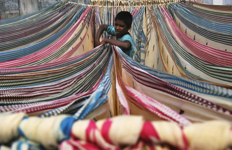 印度棉業歷史悠久，印度南部城市海得拉巴1名男孩，正在分開筆挺紗麗，繽紛顏色似乎預告印度未來經濟是彩色的。圖片來源：達志影像/路透社   