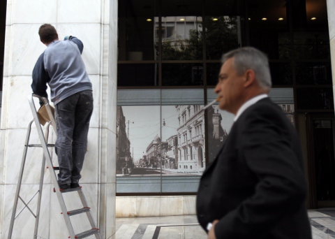 希臘換債順利，雅典一名工人在今換債截止日清理阿爾法(Alpha Bank)銀行總部大樓的大理石，迎接2年多來希債最樂觀的局面。(圖片來源:達志影像/美聯社。)   