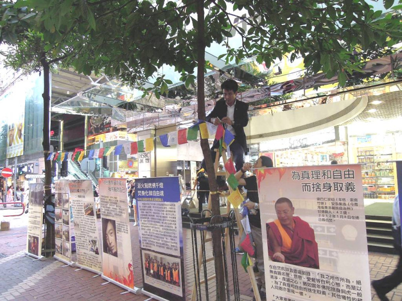 在台西藏人福利協會會長札西慈仁架梯爬上行道樹，掛起西藏的天馬旗，將止息五毒、增長五智的五色經文祝福隨風傳遞。圖：鄭凱榕/攝。   