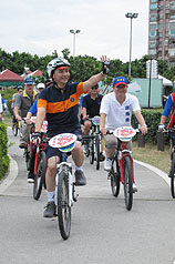 國民黨新北市長參選人朱立倫（前）29日從台北縣二重疏洪道親水公園騎自行車到八里左岸廣場，沿途向民眾揮手致意。圖片提供：中央社   