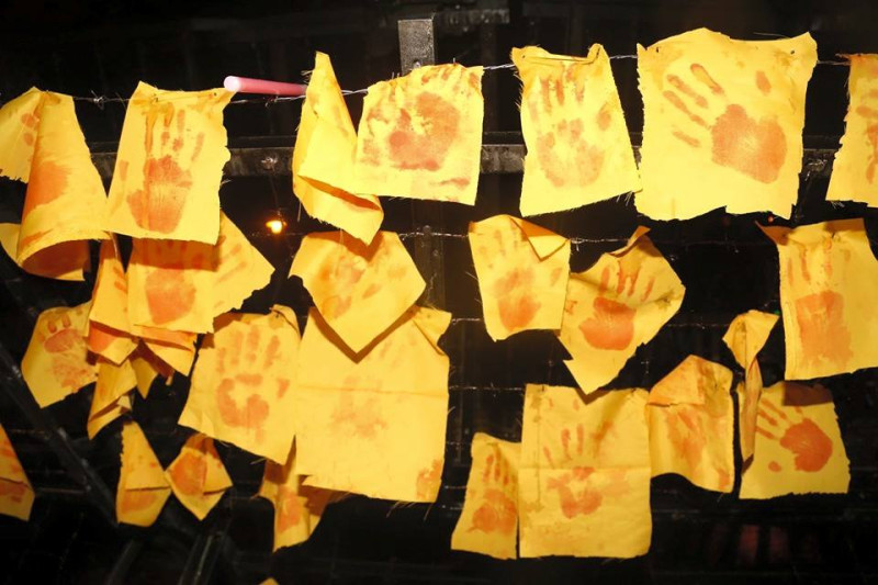 每個人將印上「血手印」的黃布掛在拒馬前，象徵去年民眾被警察所打、流的鮮血。圖：林雨佑/攝   