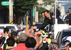 國民黨總統候選人馬英九（右）3日在花蓮市隨車隊掃街拜票，與熱情的民眾擊掌致意。圖片來源：中央社   