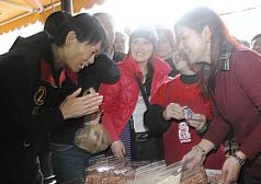 總統夫人周美青（前左）2日前往台中東勢區菜市場，親切地向民眾鞠躬拜票。圖片來源：中央社   
