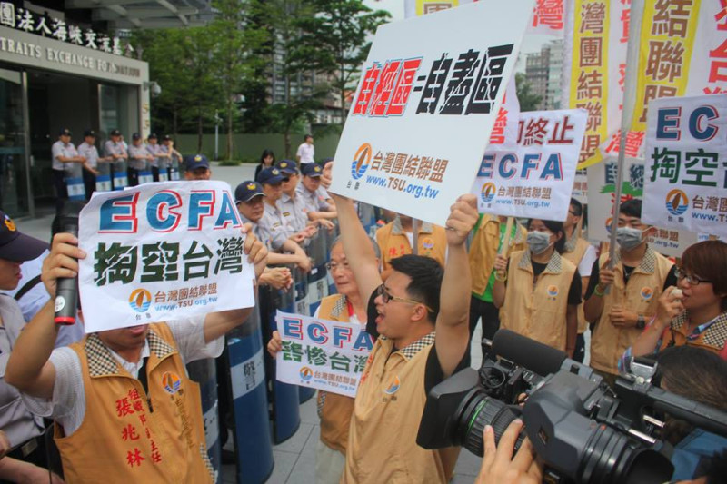 陳雲林車隊開進海基會大樓地下室，台聯多名成員在警方阻擋下，仍手舉牌子並高聲抗議。圖：林雨佑/攝   