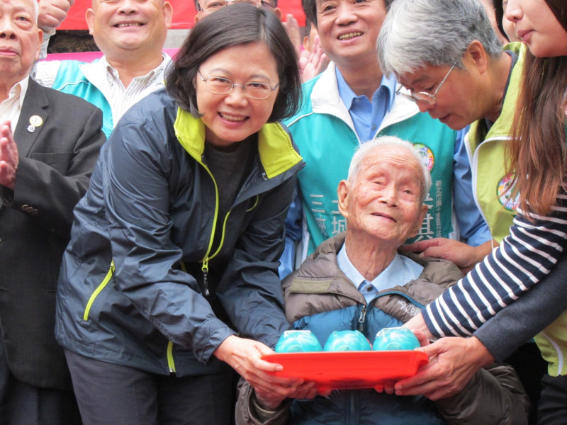 民進黨總統候選人蔡英文11日在三峽祖師廟接受108歲人瑞林（不直）阿公贈送3隻小豬撲滿。圖：林朝億/攝   