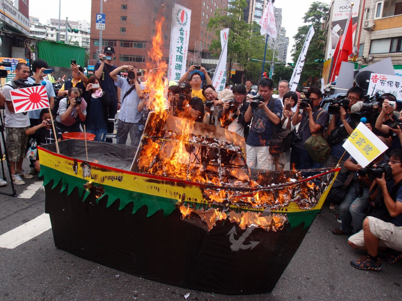 保釣團體焚燒紙做的軍艦出雲號，以示對日本軍國主義再起的抗議，現場頓時濃煙四起。圖：陳柔伊/攝   