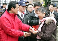 總統馬英九（左）23日大年初一赴台北市保安宮參拜，並發放金龍福袋，現場民眾依序排隊，向馬總統索取福
袋討吉利。圖片來源:中央社   