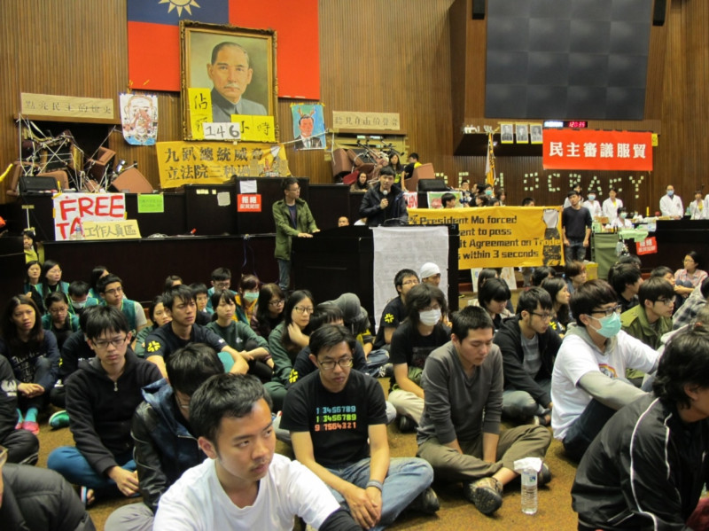 對於總統馬英九今（23）日上午10時召開記者會，在議場的學生也同時透過廣播聆聽，他們除了在議場靜坐，也在後面拉起2面大布條抗議。圖：林朝億/攝   