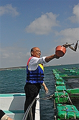 民主進步黨主席蘇貞昌「過庄行聊」行程25日到澎湖參訪箱網養殖業，並實際拿起水勺、挖起飼料魚，餵食箱網內的魚。圖片來源：中央社。   