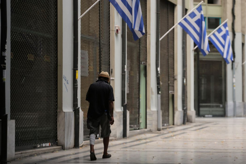 一名無家可歸的人走在雅典倒閉的商店街上。圖片來源：達志影像/美聯社。   