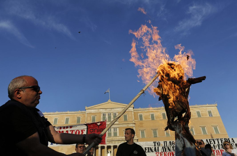 抗議希臘政府大量裁員的計畫，民眾在國會前焚燒肖像抗議。圖片來源：達志影像/路透社。   