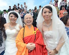 一對相戀7年的女同志「美瑜」（左）與「雅婷」（右）11日在釋昭慧法師（中）見證下，完成佛教儀式的婚禮。圖片來源：中央社   
