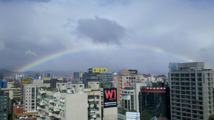 台北市今（26日）晨還在下毛毛細雨，不過上午陽光露臉，將早上下過雨的潮溼空氣映成一個一個彩虹。圖片來源：翻攝自臉書網友   