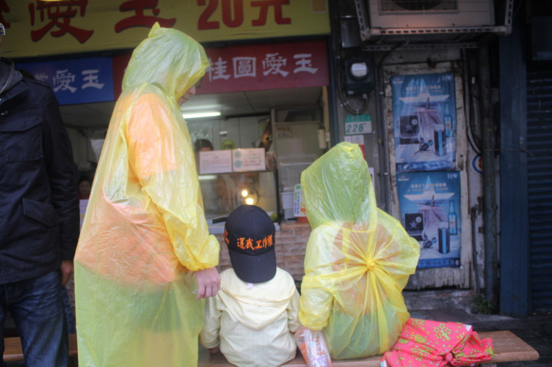 前國道收費員陳媽媽今（12）日帶著今年9歲念小四的女兒和3歲的兒子穿著雨衣，到國民黨黨部前抗議。圖：林雨佑/攝   