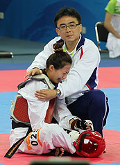 跆拳道選手楊淑君（前）17日在廣州亞運女子49公斤級賽，不甘突然被大會取消資格，坐在場上抗議。中華隊教練（後）心疼她所受的委屈，上場擁抱安慰。圖片來源：中央社   