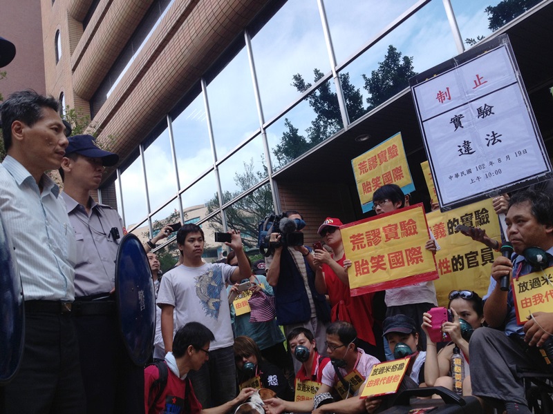 農委會防檢局副局長馮海東（左一）今（19）日由帶著盾牌的警察保護，出面回應抗議民眾的訴求。右一為動保人士黃泰山。圖：王立柔/攝   
