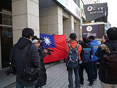 世跆盟大樓,門前有兩名台灣留學生高舉一面大型國旗為楊淑君加油打氣。圖片來源:中央社