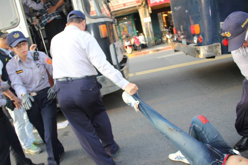 一名警察只拉著收費員的長褲褲腳，就拖著往前走。圖3之2：林雨佑/攝   