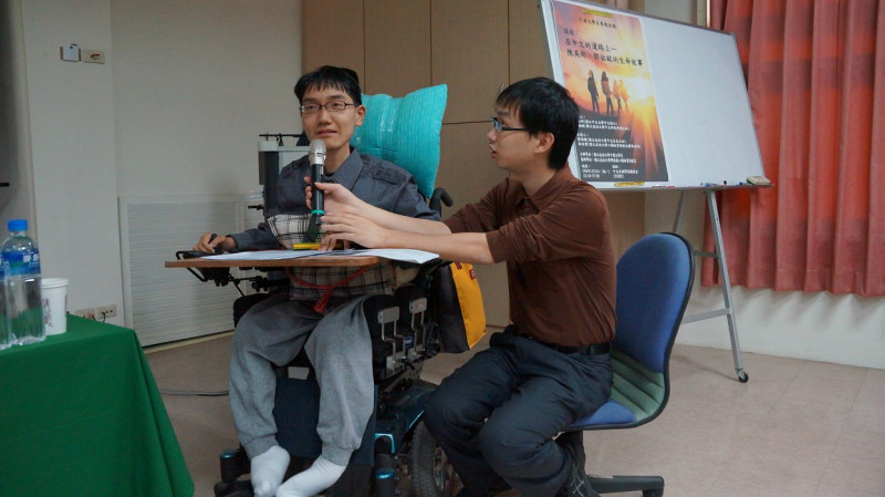 罹患罕見疾病裘馨氏肌肉萎縮症，須仰賴電動輪椅甚至要配戴呼吸器的成大中文系碩士生郭祐銘（左）應邀發表演講，鼓舞其他學子珍惜生命，努力學習。圖：黃博郎/攝   
