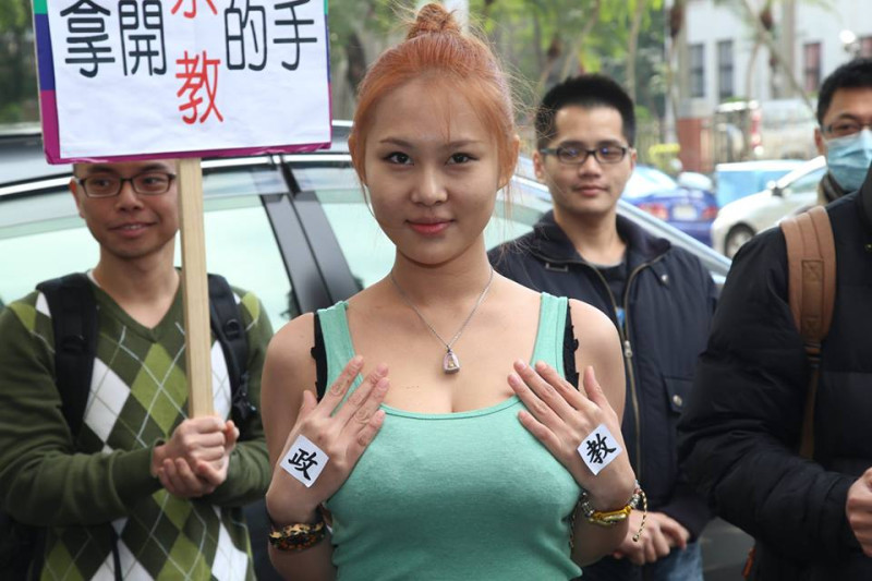 馬友蓉在雙手分別貼上「政」、「教」二字，並放在胸前，象徵「政教分離」。圖2之1：林雨佑/攝   