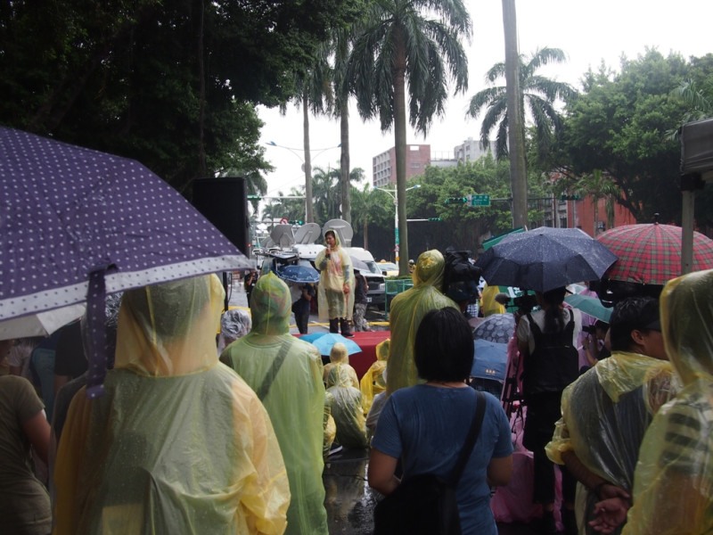 22日下午4點多，現場下起大雨，主辦單位立即發送雨衣給現場民眾，民眾紛紛穿上雨衣，繼續於現場守候。圖:何星瑩/攝   