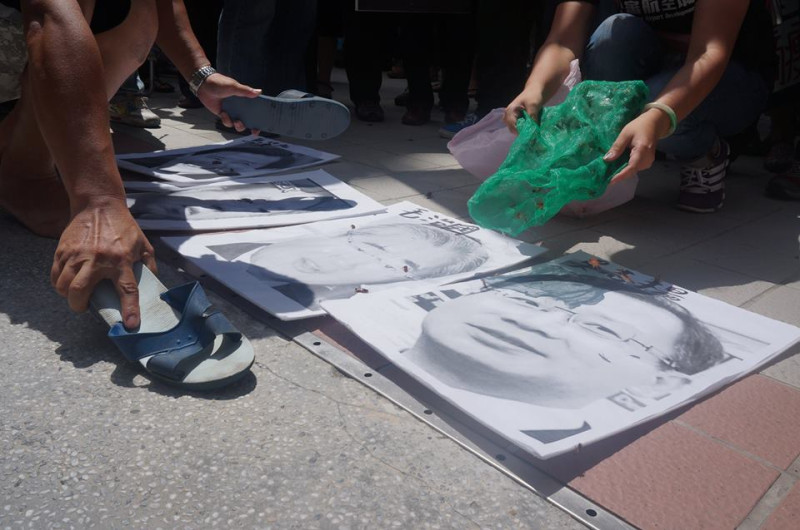 反對桃園航空城的桃園居民今(29)天在營建署門口上演行動劇，拿藍白拖鞋打象徵「炒地蟑螂」的官員肖像。圖:陳芛薇/攝。   