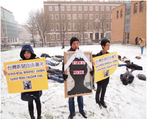 台灣在英國留學生在倫敦大學亞非學院被白雪覆蓋的廣場上，手持台灣媒體「遺照」、頭覆黑巾躺臥雪地，表達對媒體壟斷的憂心。圖:賴慧玲攝影   